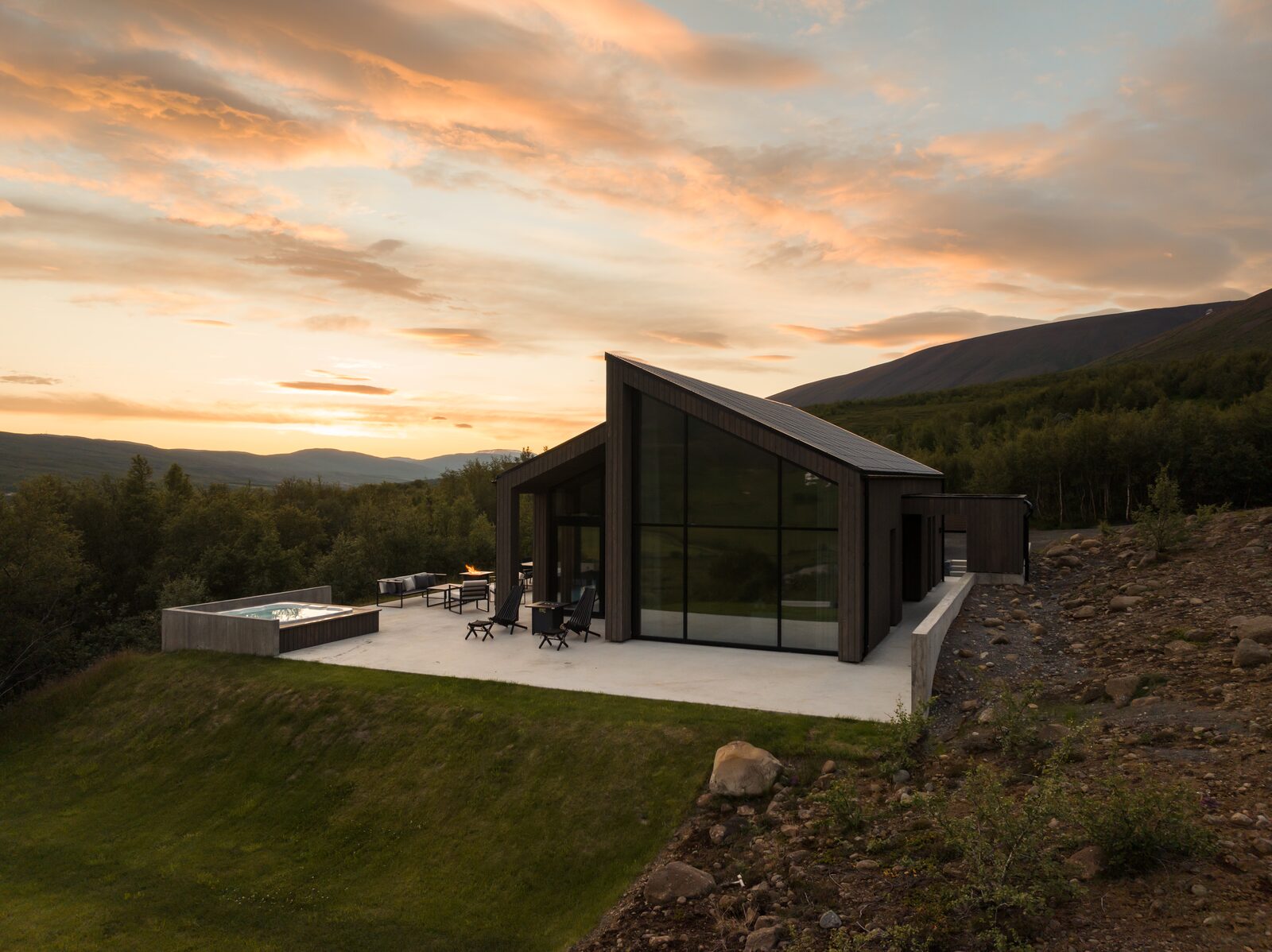 An aerial view of the house and terrace at Lundskógur beneath an orange and pink evening sky.