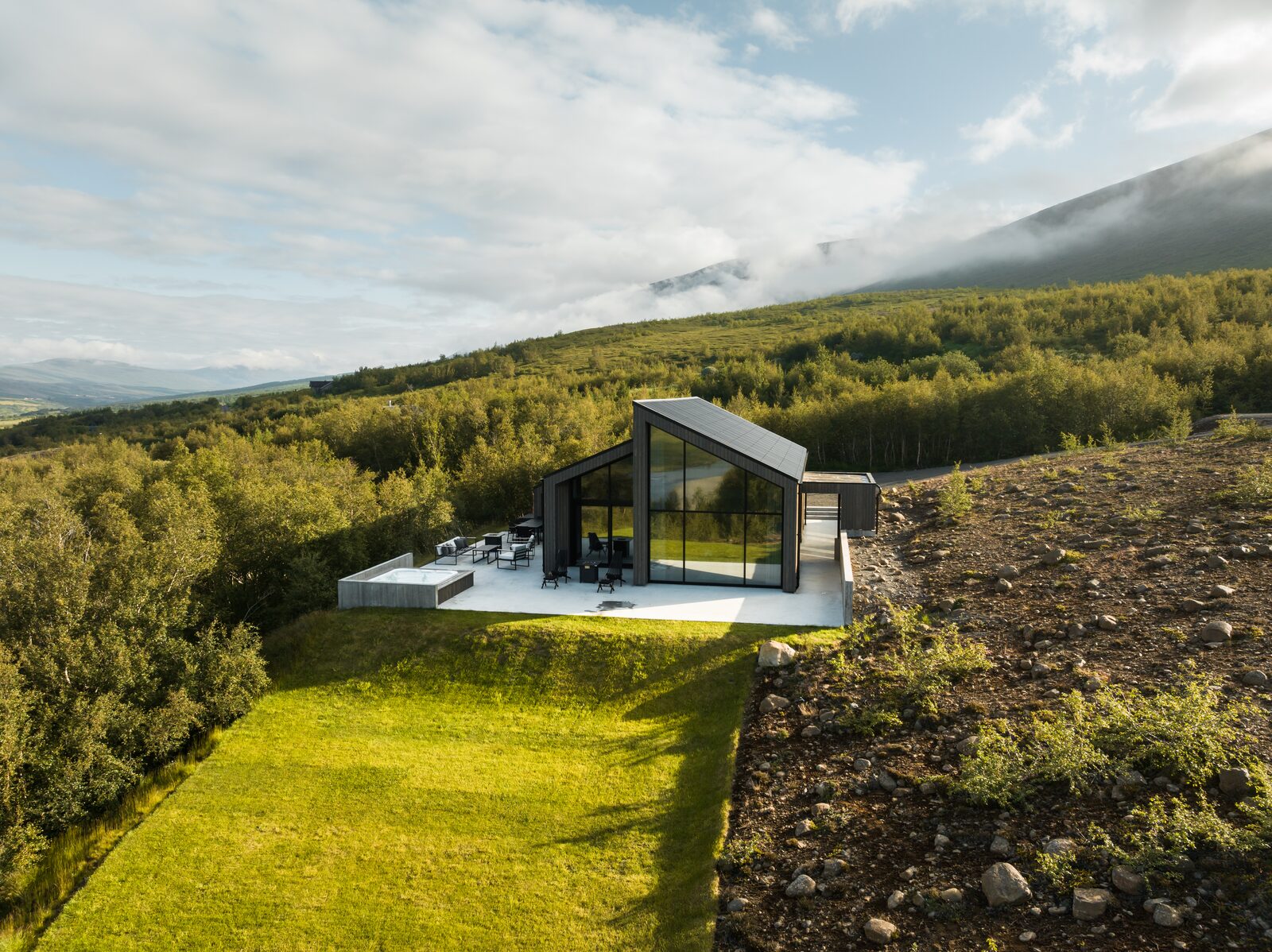 An aerial view of the house and hot-tub terrace at Lundskógur in warm evening light.