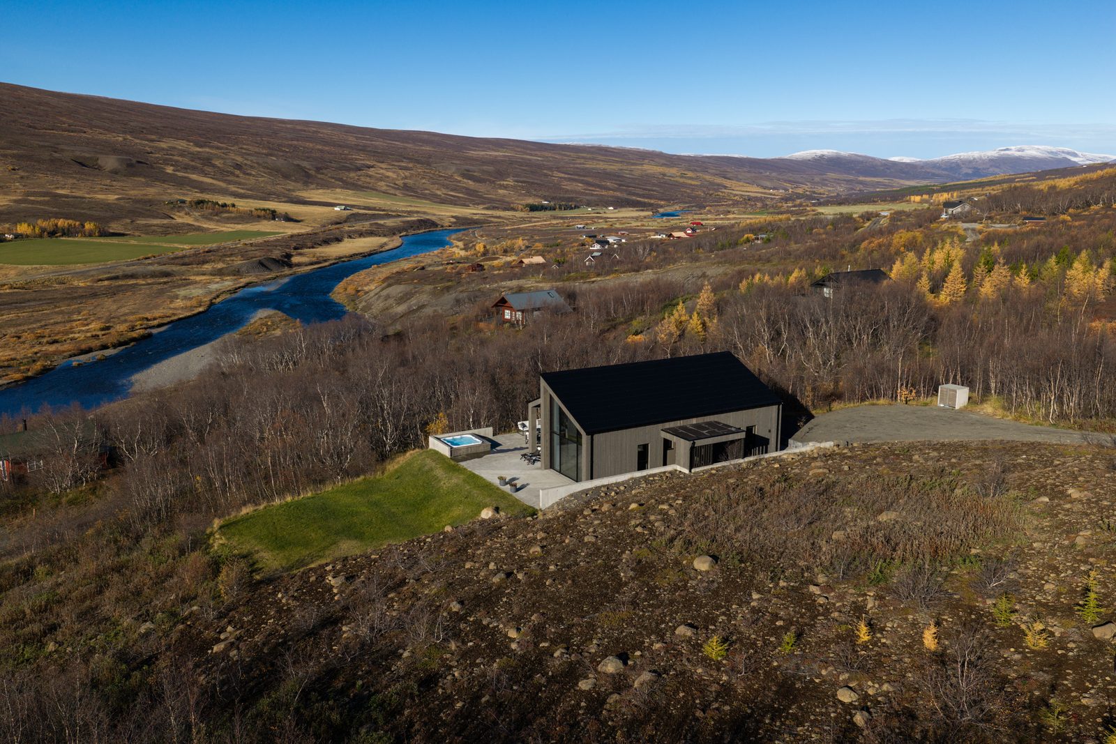 An aerial view over Fnjóskadalur in autumn, with the river winding below the house at Lundskógur on its hillside.