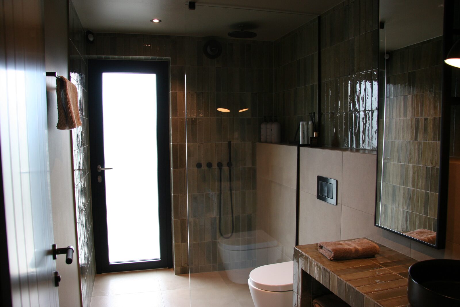 The main bathroom, with a tiled shower and a glazed door bringing in daylight.