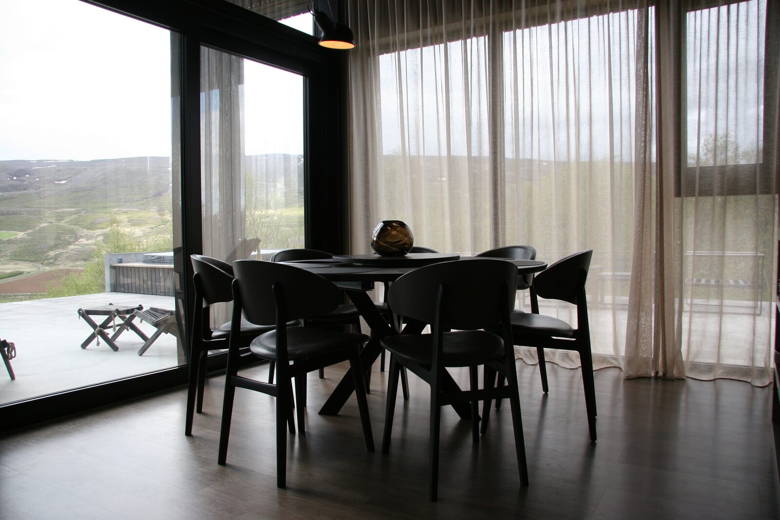 The round dining table beside a full-height window looking onto the terrace.