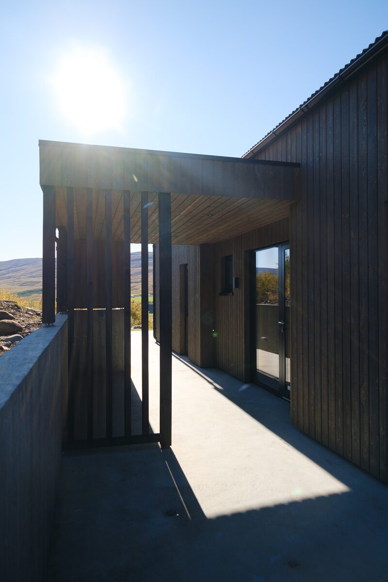 The covered concrete walkway along the side of the house at Lundskógur.