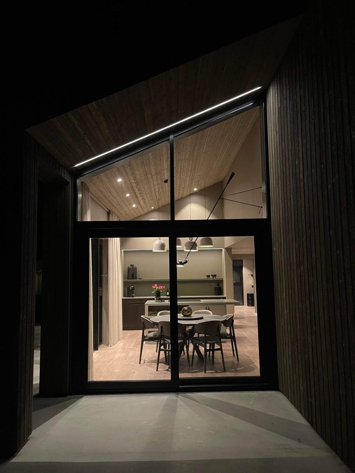 The dining area lit inside the glass gable at Lundskógur at night.