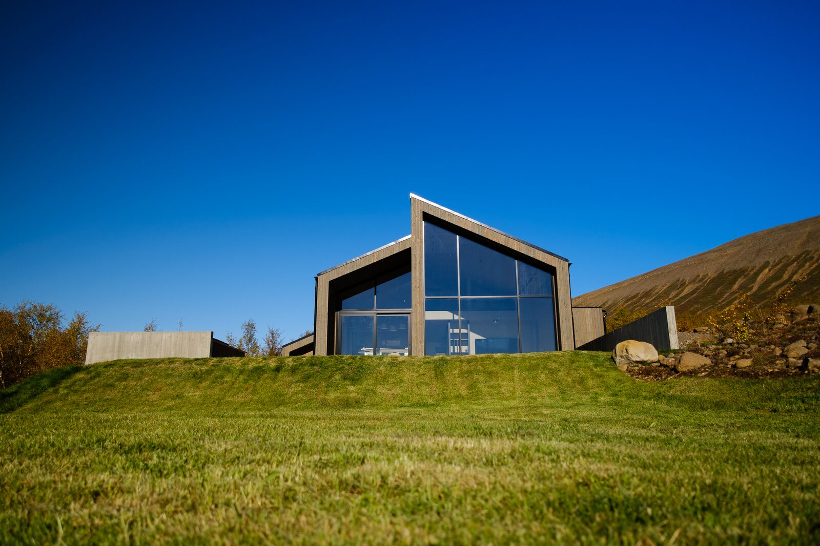A wide daytime view of the house at Lundskógur with the hills of Fnjóskadalur behind.