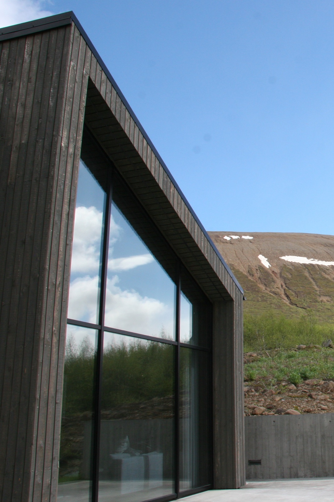 The hot tub terrace behind the house at Lundskógur in daylight.