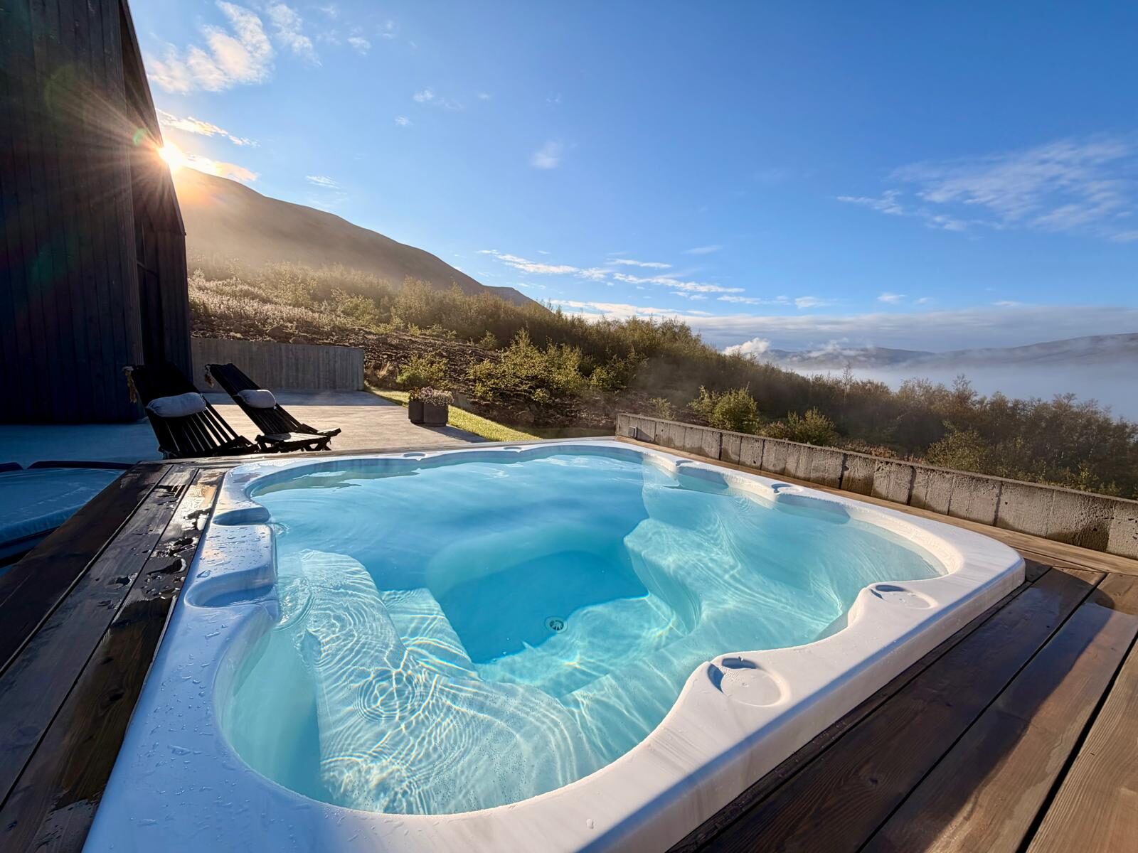 The private hot tub and two deck chairs on the terrace beneath a clear sky.