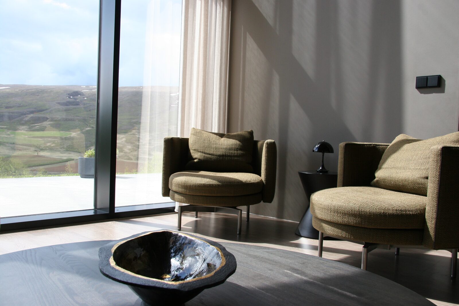 Two armchairs and a round coffee table beside the floor-to-ceiling windows.