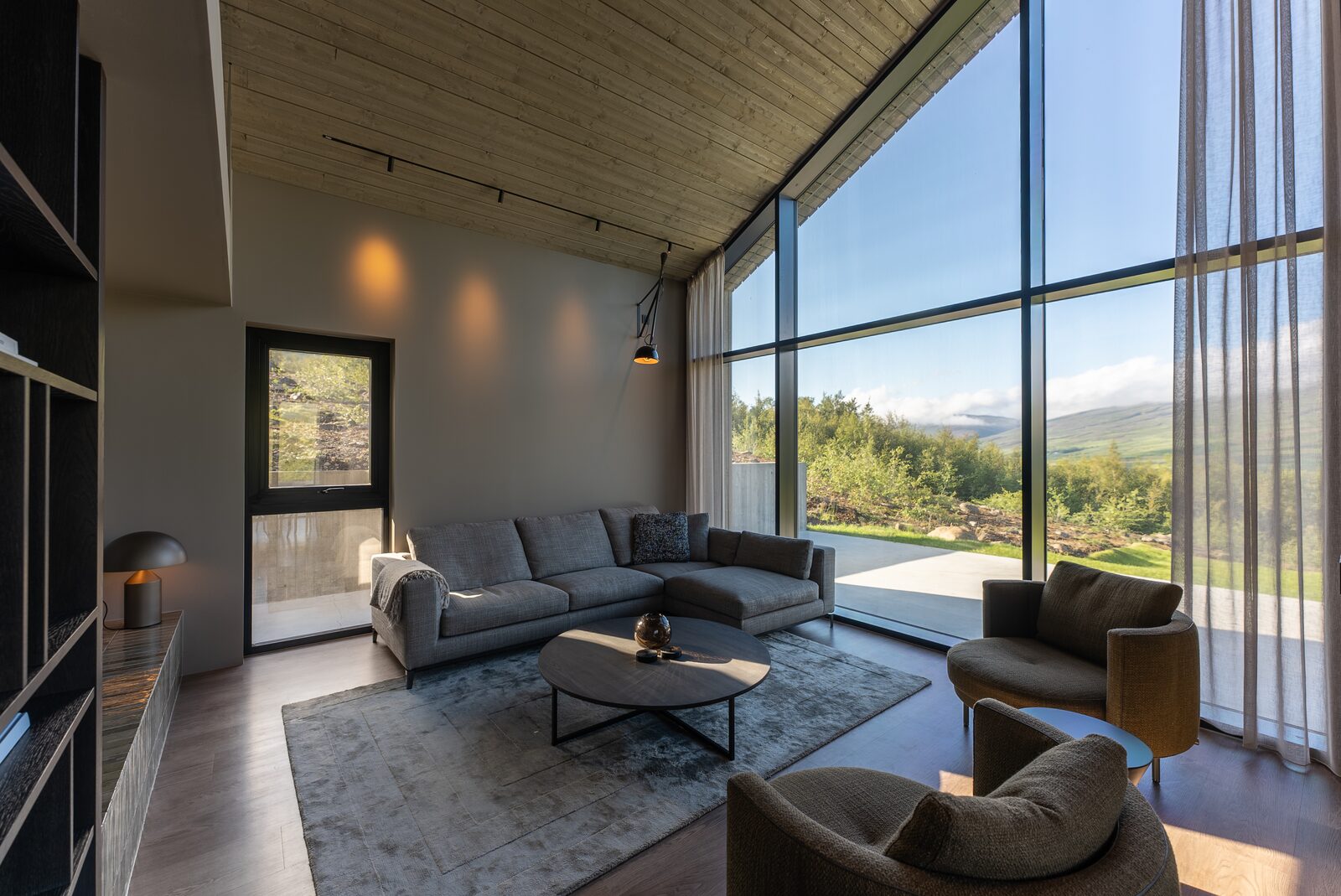 The living area sofa and coffee table with Fnjóskadalur visible through the glass wall.