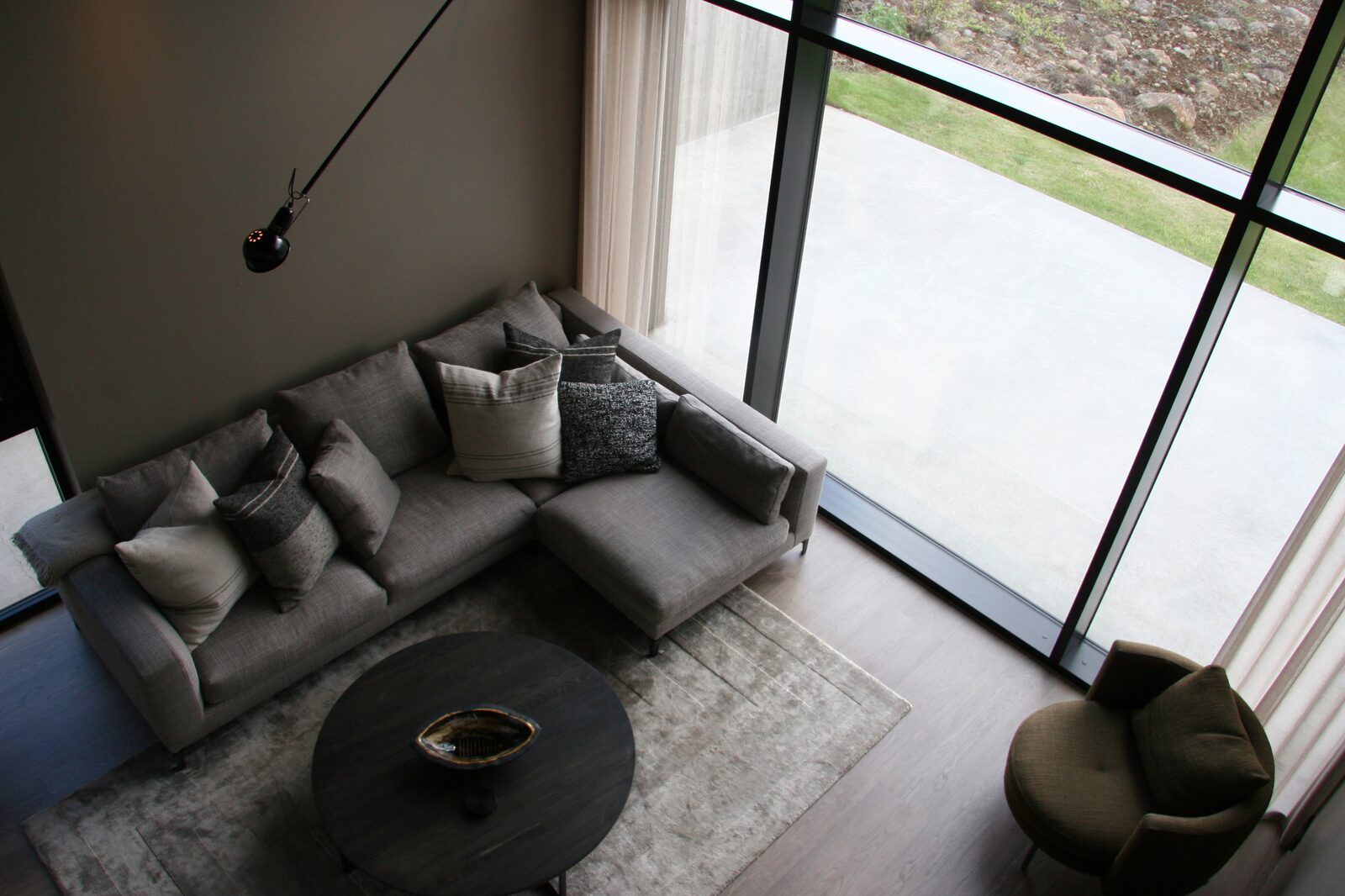 The living area sofa beside the floor-to-ceiling glass wall opening onto the terrace.