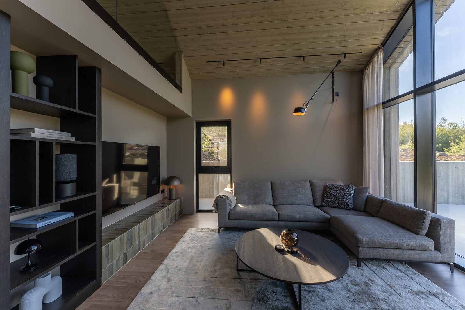The living area with a sectional sofa, round coffee table and full-height windows over the valley.
